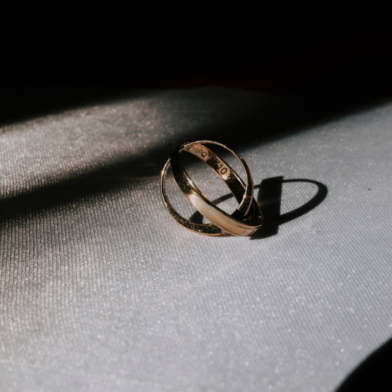 Two intertwined, gold rings on a table.
