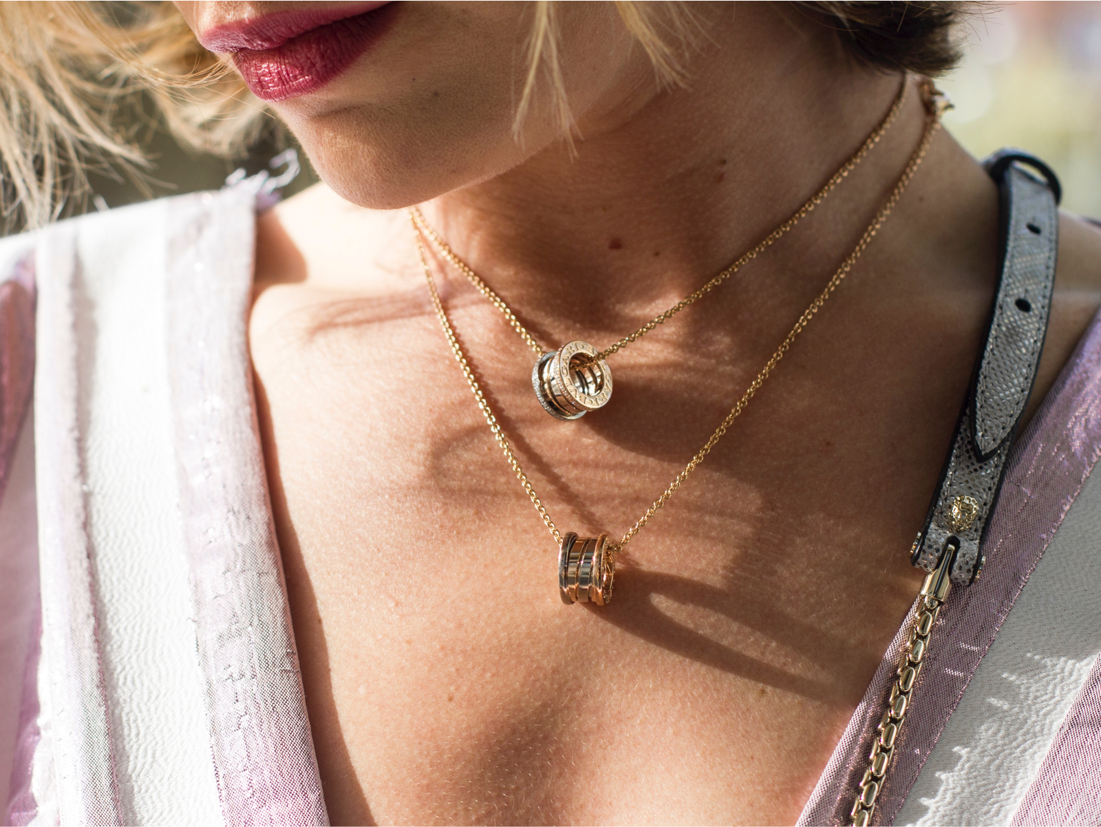A woman's neck with 2 matching necklaces. Each necklace has a silver charm hanging on it.