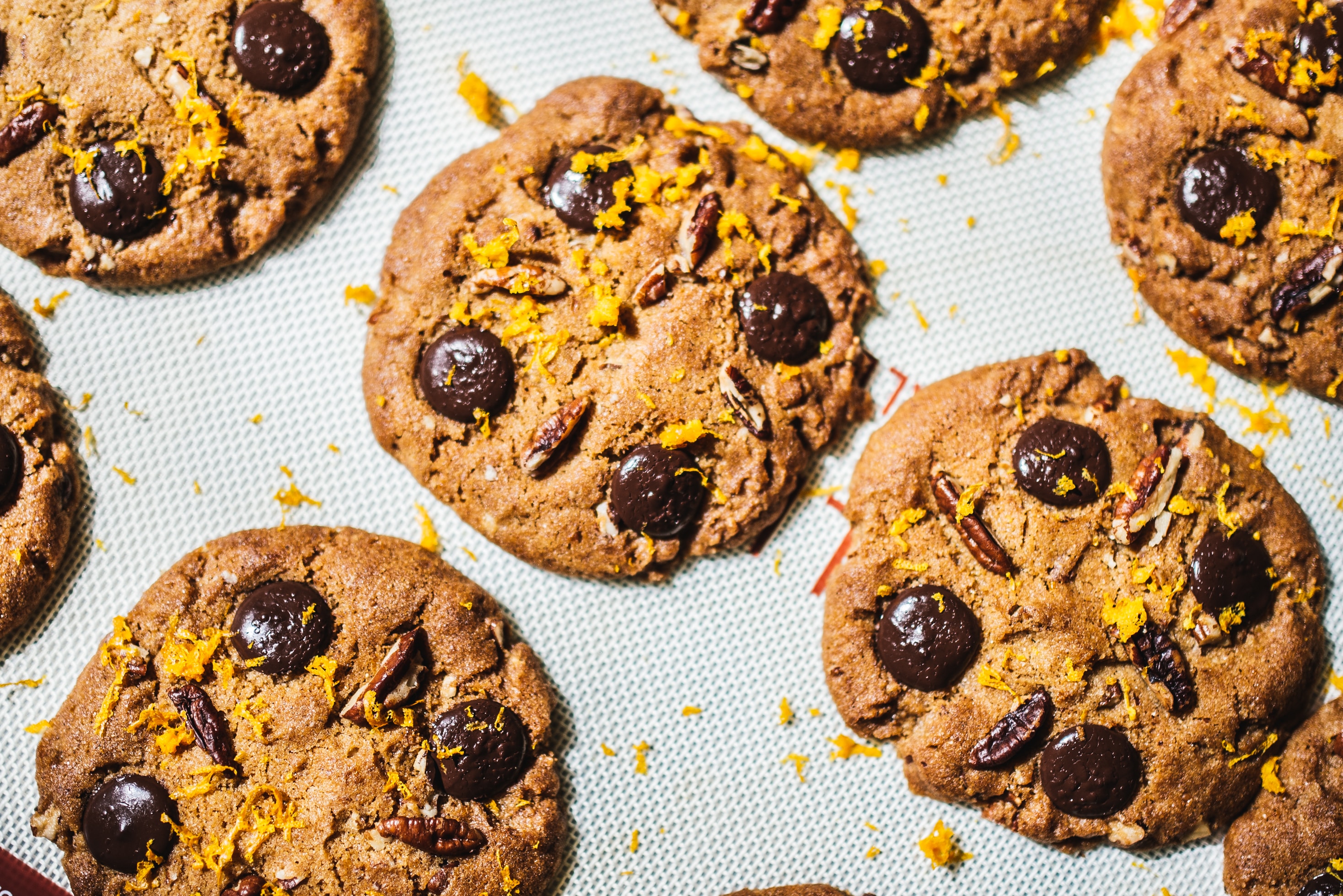A bunch of chocolate chip cookies with nuts and lemon zest.