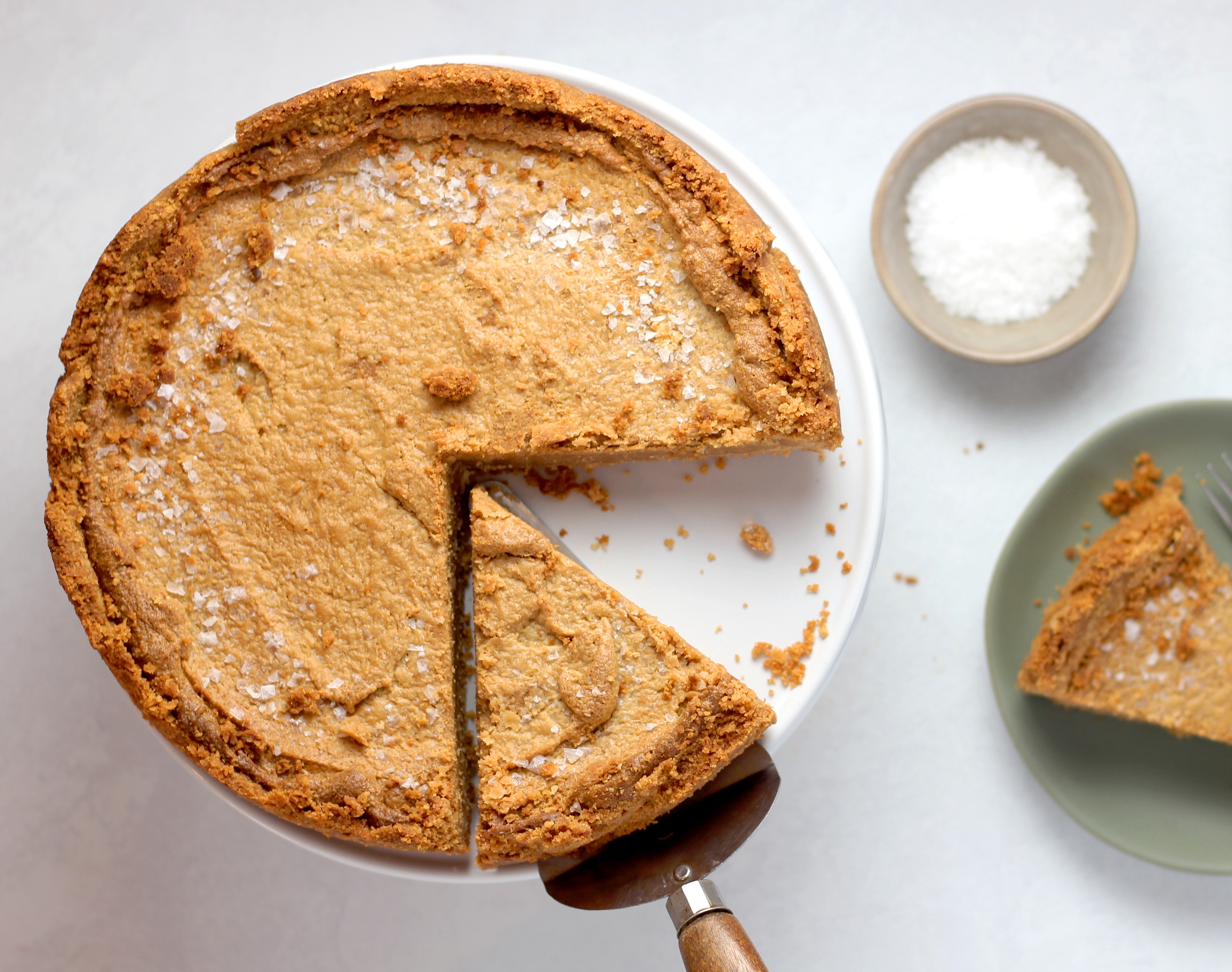 A pumpkin pie with a slice cut out of it on a round, white tray.