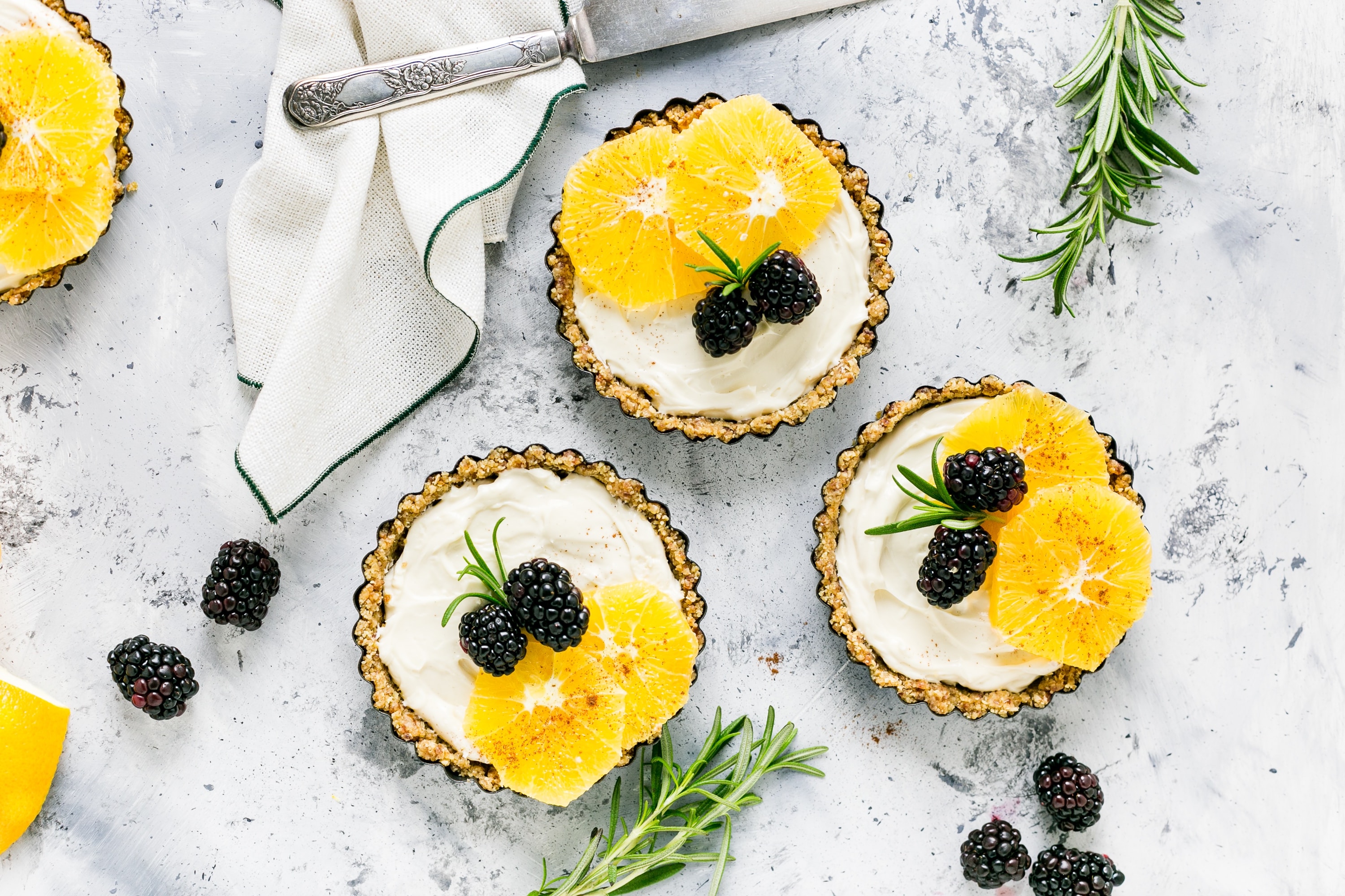 A few tarts with fresh orange and blackberries on top as garnish.