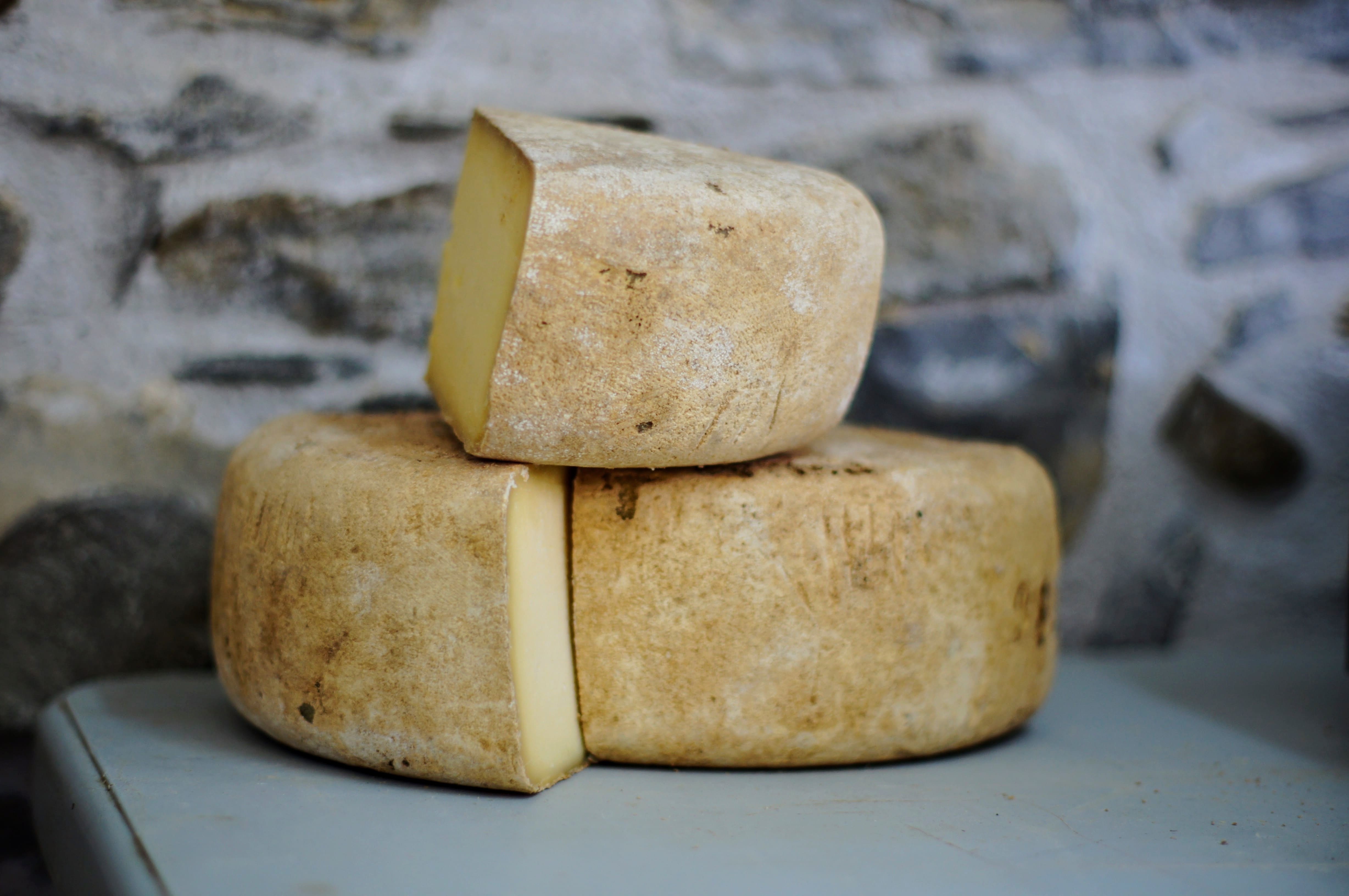 A wheel of smoked cheddar cheese cut in quarters.