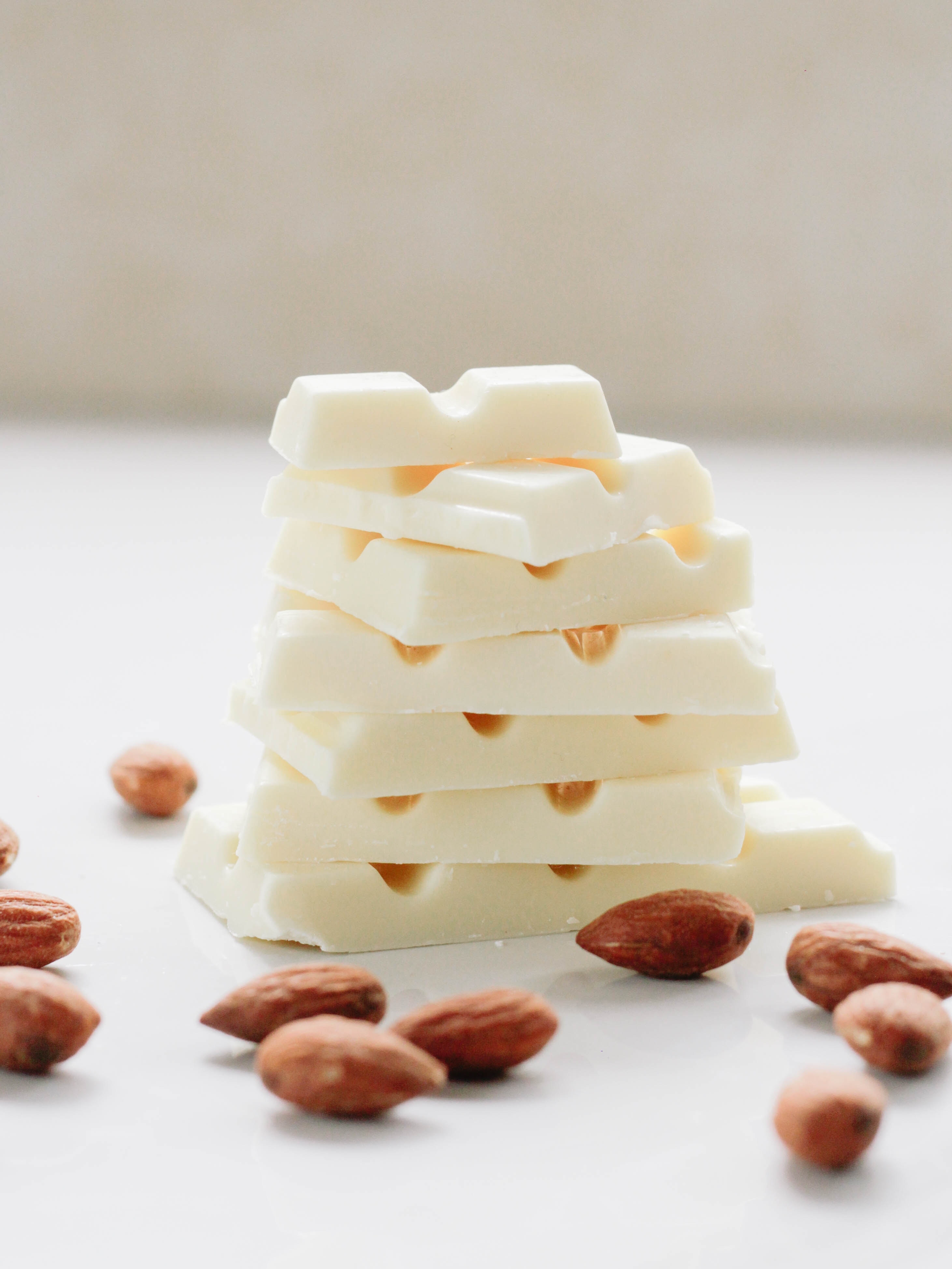 A stack of white chocolate bars with almonds laying in front on the counter.